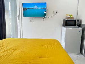 1 dormitorio con cama amarilla y TV en la pared en Ocean Pearl - A brand new one bedroom with pool, walkable distance to sunset beach en Long Bay Hills
