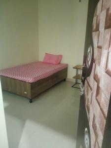 a small bedroom with a bed with a pink pillow at OYO Bhavya Guest House in Morādābād
