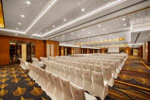 Radisson Blu Hotel GRT, Chennai International Airport في تشيناي: قاعة احتفالات مع كراسي بيضاء في غرفة