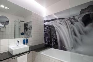 a bathroom with a sink and a waterfall painting on the wall at Radisson Blu 1919 Hotel, Reykjavík in Reykjavík