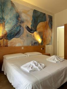 a bedroom with a bed with a painting on the wall at Hotel LA MAISON by Aldebaran in Lido di Jesolo