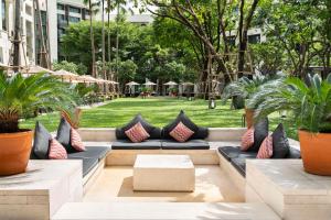 a patio with couches and plants in a park at Siam Kempinski Hotel Bangkok - SHA Extra Plus Certified in Bangkok