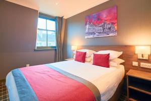 a bedroom with a large bed with two red pillows at Best Western Glasgow Hotel in Glasgow