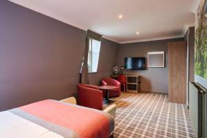 um quarto de hotel com uma cama e cadeiras e uma televisão em Best Western Glasgow Hotel em Glasgow