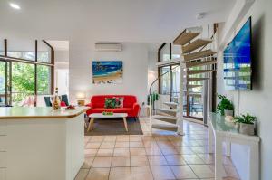 a living room with a red couch and a staircase at Ocean Breeze Resort in Noosa Heads