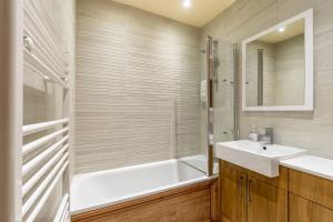un bagno con vasca, lavandino e specchio di Studio Cottage ad Ambleside Altre 8 foto