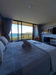 a bedroom with a large bed with a view of the ocean at Casa Yogui Brasil in Garopaba