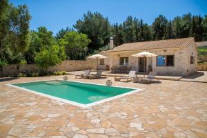 a villa with a swimming pool in front of a house at Villa Stamateli, Antipaxos in Antípaxos