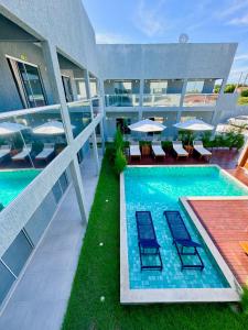 una piscina en un edificio con sillas y mesas en Apartamento localizado em condomínio fechad0 em Barra Grande - PI en Parnaíba