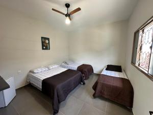a room with two beds and a ceiling fan at casa inteira com 3 suites e área de lazer in Delfinópolis
