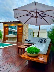 un patio con sofá y una sombrilla en una terraza en Apartamento localizado em condomínio fechad0 em Barra Grande - PI en Parnaíba