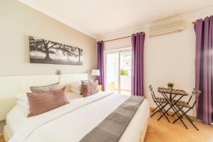 1 dormitorio con 1 cama blanca grande con cortinas moradas en Oasis Beach Apartments, en Luz