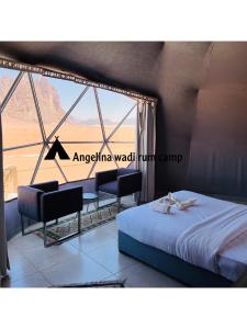a bedroom with a bed and chairs and a window at Angelina Wadi Rum camp in Wadi Rum