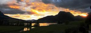 a sunset over a body of water with mountains at Pension Essbaum in Walchsee