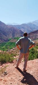 een man op een heuvel die naar de bergen kijkt bij Dar Imoughlad in Marrakesh