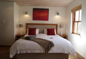 a bedroom with a large white bed with red pillows at La Baleine in Paternoster