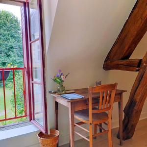 een houten bureau in een kamer met een raam bij La Moyendrie in Les Montils
