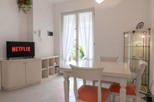 a white dining room with a table and a tv at Villini Al Vittoriale in Gardone Riviera