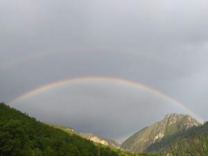 Ein Regenbogen am Himmel über einigen Bergen in der Unterkunft Family owned self sufficient ECO farm TARA in Pljevlja