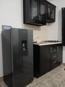 a kitchen with black cabinets and a refrigerator at Estudios Manzanilla in Puerto Peñasco