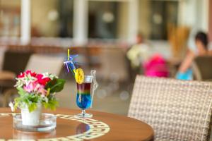 a table with a drink and a vase of flowers at Pine House by Werde Hotels in Kemer
