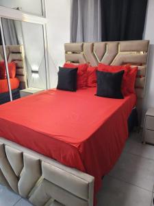 uma cama grande com lençóis vermelhos e almofadas pretas em Aparta estudio en santiago #1 em Santiago de los Caballeros