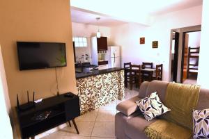 a living room with a couch and a flat screen tv at Apto bem equipado, com 2 quartos acomoda até 6 pessoas confortavelmente in Ubatuba