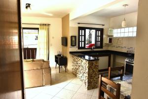 a kitchen and living room with a couch and a counter at Apto bem equipado, com 2 quartos acomoda até 6 pessoas confortavelmente in Ubatuba