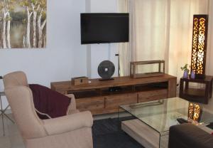 ein Wohnzimmer mit einem TV, einem Sofa und einem Tisch in der Unterkunft Sunbirds Chobe Hotel in Kasane