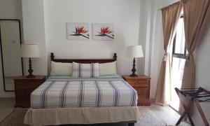 カサネにあるSunbirds Chobe Hotelのベッドルーム1室(ベッド1台、ランプ2つ、窓付)