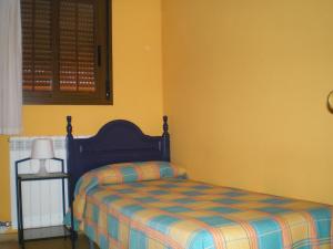 ein Schlafzimmer mit einem Bett in einem gelben Zimmer in der Unterkunft Apartamentos Turísticos Reyes Católicos in Saragossa