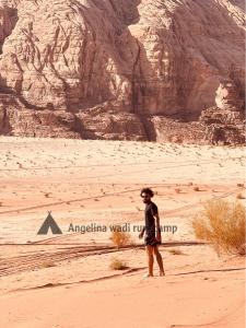 a man standing in the desert near a mountain at Angelina Wadi Rum camp in Wadi Rum