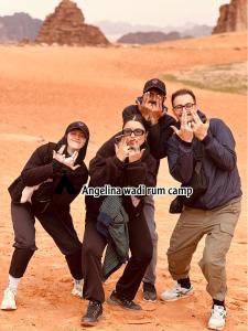a group of people posing for a picture in the desert at Angelina Wadi Rum camp in Wadi Rum