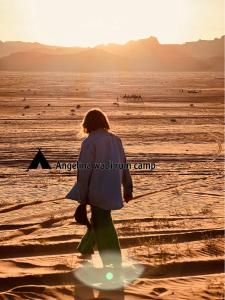 a woman walking through the desert at sunset at Angelina Wadi Rum camp in Wadi Rum