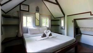 un dormitorio con una cama blanca con zapatos. en The Piupiu Nest, en Iriga City