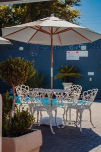 - une table et des chaises sous un parasol sur la terrasse dans l'établissement Pousada Iguassu Charm Suites, à Foz do Iguaçu