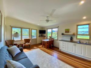 a living room with a blue couch and a kitchen at Mountain View Tilba Tilba in Tilba Tilba