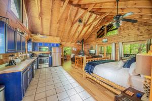 a bedroom in a log cabin with a bed and a kitchen at Love Me Tender Studio Cabin in Sevierville