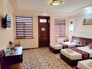 Cette chambre comprend deux lits et un bureau. dans l'établissement Hotel Shams, à Boukhara