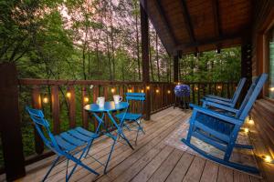 une terrasse couverte avec des chaises bleues et une table sur une terrasse dans l'établissement Love Me Tender Studio Cabin, à Sevierville