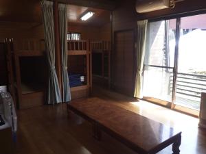 ein Wohnzimmer mit Tisch und großem Fenster in der Unterkunft キャンプ&リゾート立山山麓家族旅行村 in Tateyama