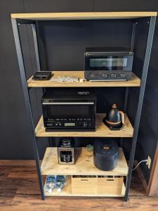 a shelf with a microwave and a toaster oven at 雨の日でもバーベキューで余市の食と海を楽しめる屋根付きウッドデッキと広い庭のくつろげる貸切一軒家 in Oshoro