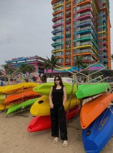 a woman standing in front of kayaks on the beach at Flamigo Ibiza Hải Tiến Tầng 16 in Nam Khê