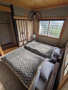 a bedroom with a large bed in a room with windows at 雨の日でもバーベキューで余市の食と海を楽しめる屋根付きウッドデッキと広い庭のくつろげる貸切一軒家 in Oshoro