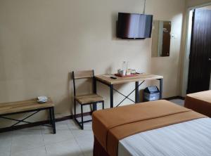a hotel room with a bed and a desk and a television at wisma sejahtera hotel in Magelang