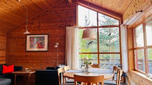a dining room with a table and a large window at Fjordhytte-3 in traumhafter Lage 100 Meter vom Hardangerfjord, Motorboot mietbar in Ænes