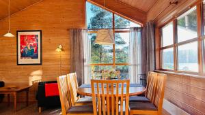 a dining room with a table and chairs and windows at Fjordhytte-2 am Hardangerfjord, grandioses Fjordpanorama, 20 PS Motorboot mietbar! in Ænes