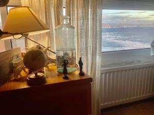 ソペラーナにあるVistas al marの窓のあるテーブルの上のランプとボトル