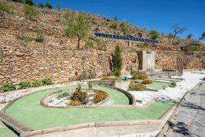einen Garten mit Blumen vor einer Steinmauer in der Unterkunft farmhouse San Marcos in Laroya