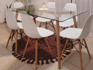 uma mesa de vidro com quatro cadeiras brancas à volta em "Valentino hostel" em Ezeiza